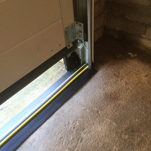 A notched garage door threshold seal fitting around the garage door frame creating a watertight seal