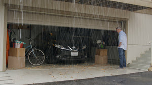 Man standing outside of garage in the rain, without a fitted garage door threshold seal kit
