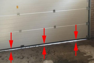 An image of a garage door with arrows pointing to the gap between the garage door and floor